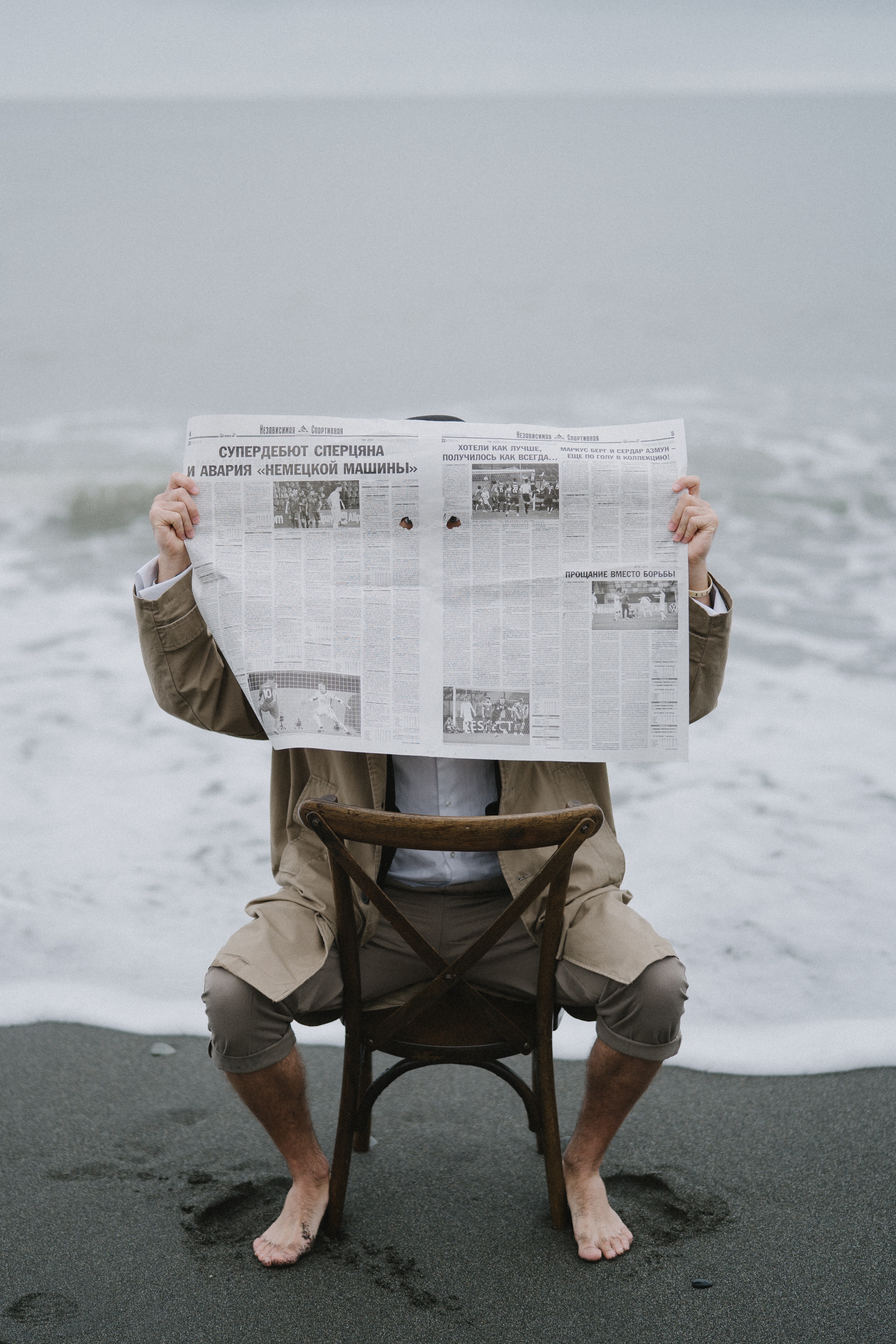 Мужчина на пляже читает газету