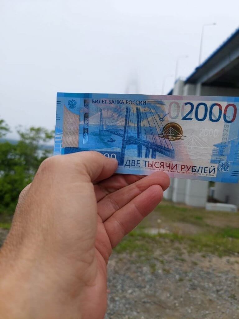 Золотой мост во Владивостоке на фоне 2000 рублей в руках